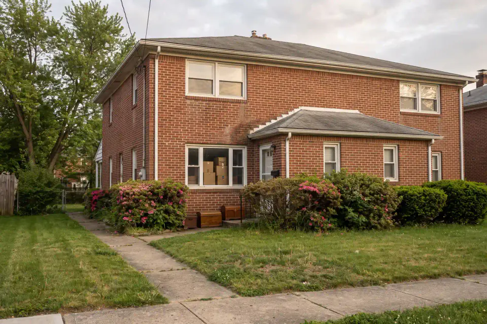 Inherited brick twin with family boxes beside a quiet front window